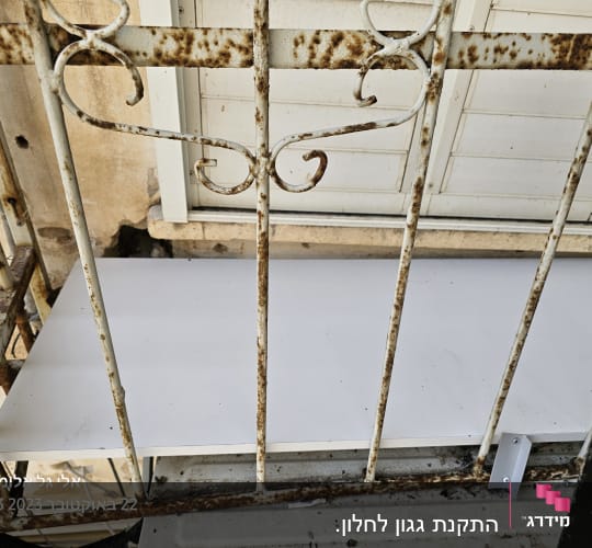מדף אלומיניום מותקן מאחורי סורג חלוד